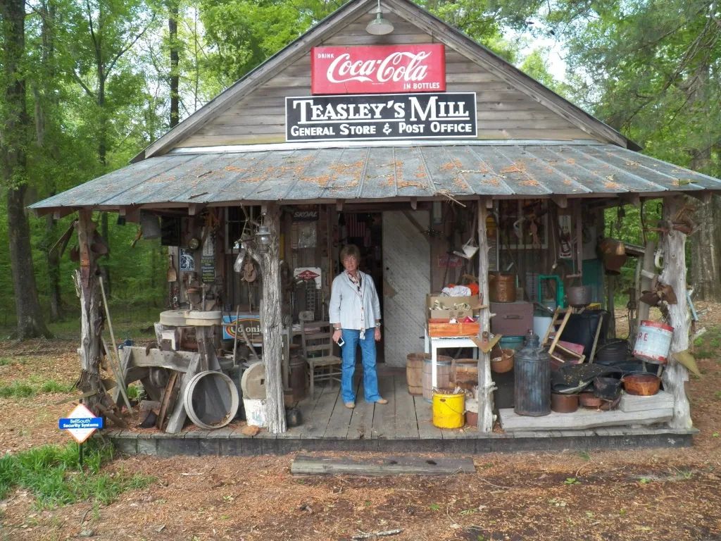 A woman stands out front of a general store that's also a post office