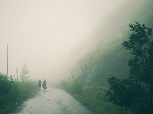 Mom and Son walking on the road in rain during a misty day thumbnail