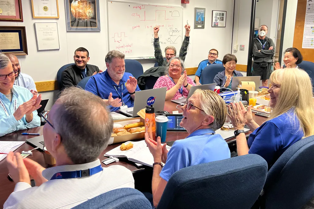 Voyager 1 team celebrating around a table
