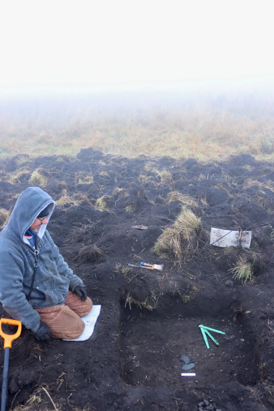 Archaeologists digging at a site in the ground