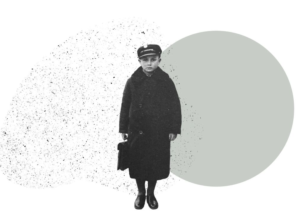 A boy in a long wool coat and hat holds a small case