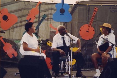 Trumpeter and bandleader Doc Paulin, being interviewed at 1995 New Orleans Jazz & Heritage Festival. His wife to the left of photo; interviewer at right.