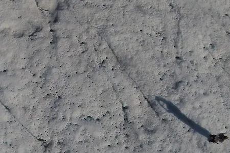 A drone shot of a researcher collecting data on cryoconite holes on the Greenland Ice Sheet.