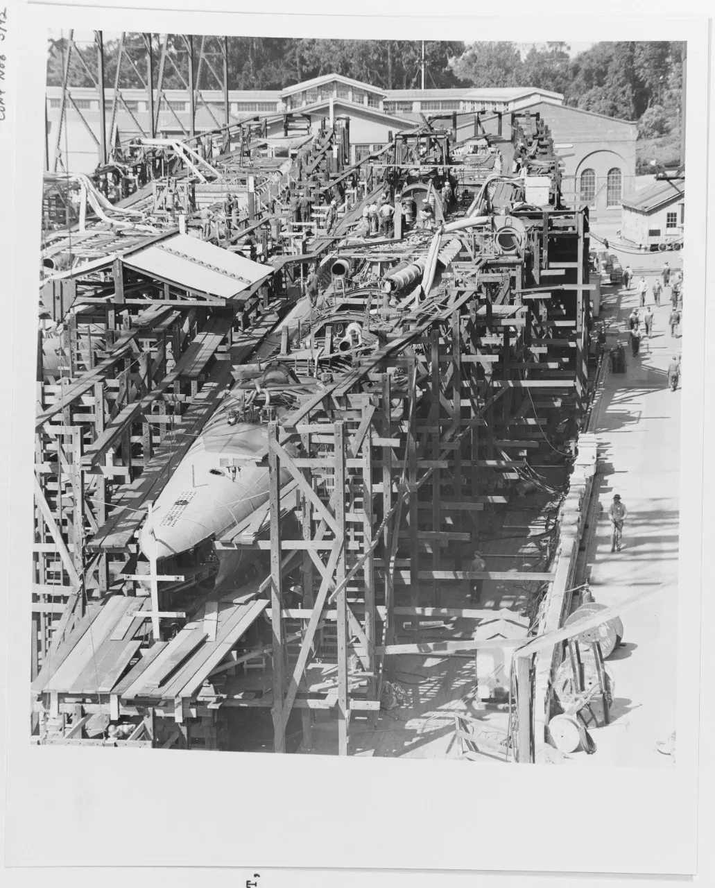 A black and white photo showing the construction of two submarines
