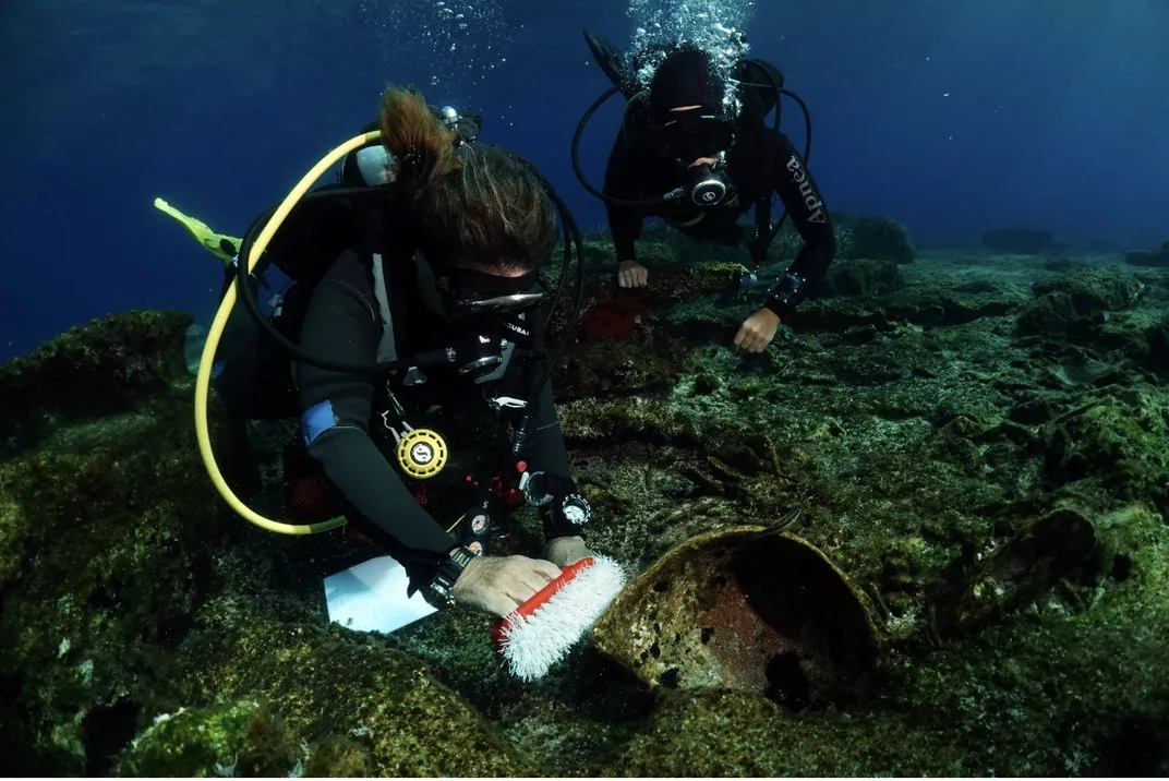 Underwater archaeologist scrubbing artifact with brush