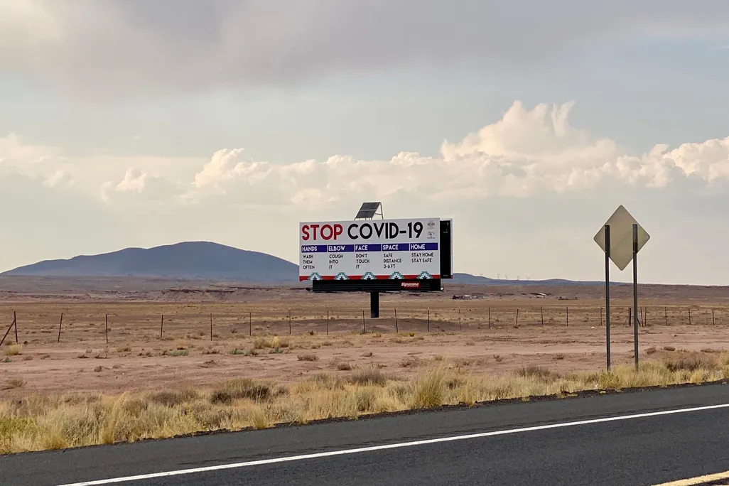 A billboard that reads "STOP COVID-19" stands out in the desert along Route 89 in Arizona