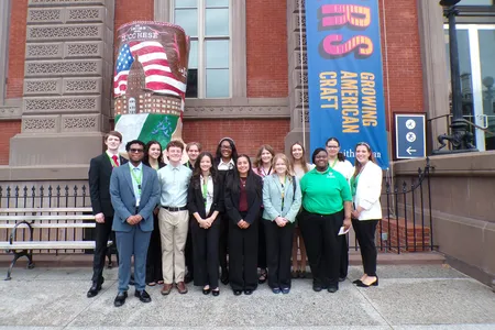 A group of teens stand in front of the Renwick Building for a group photo