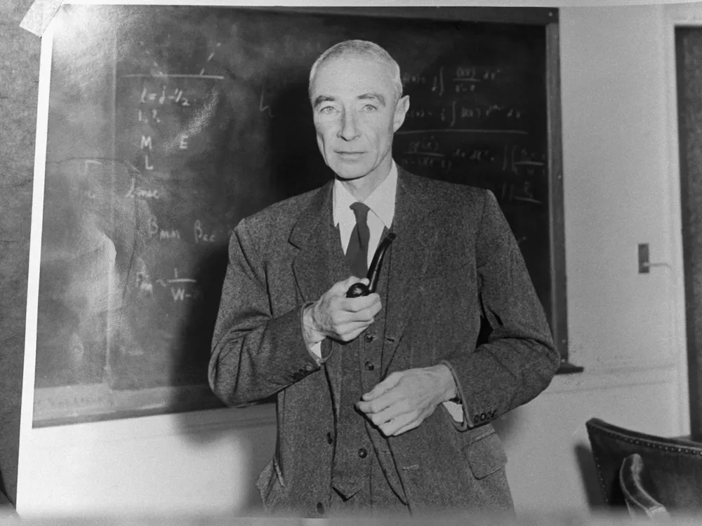 J. Robert Oppenheimer in black and white in front of a chalkboard