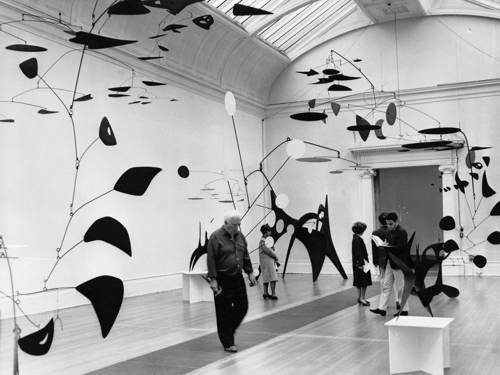 Alexander Calder checks some of his mobiles during a 1962 exhibition of his work at Tate London