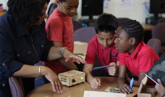 Teacher and three elementary students using Traveling Trunk content in the classroom