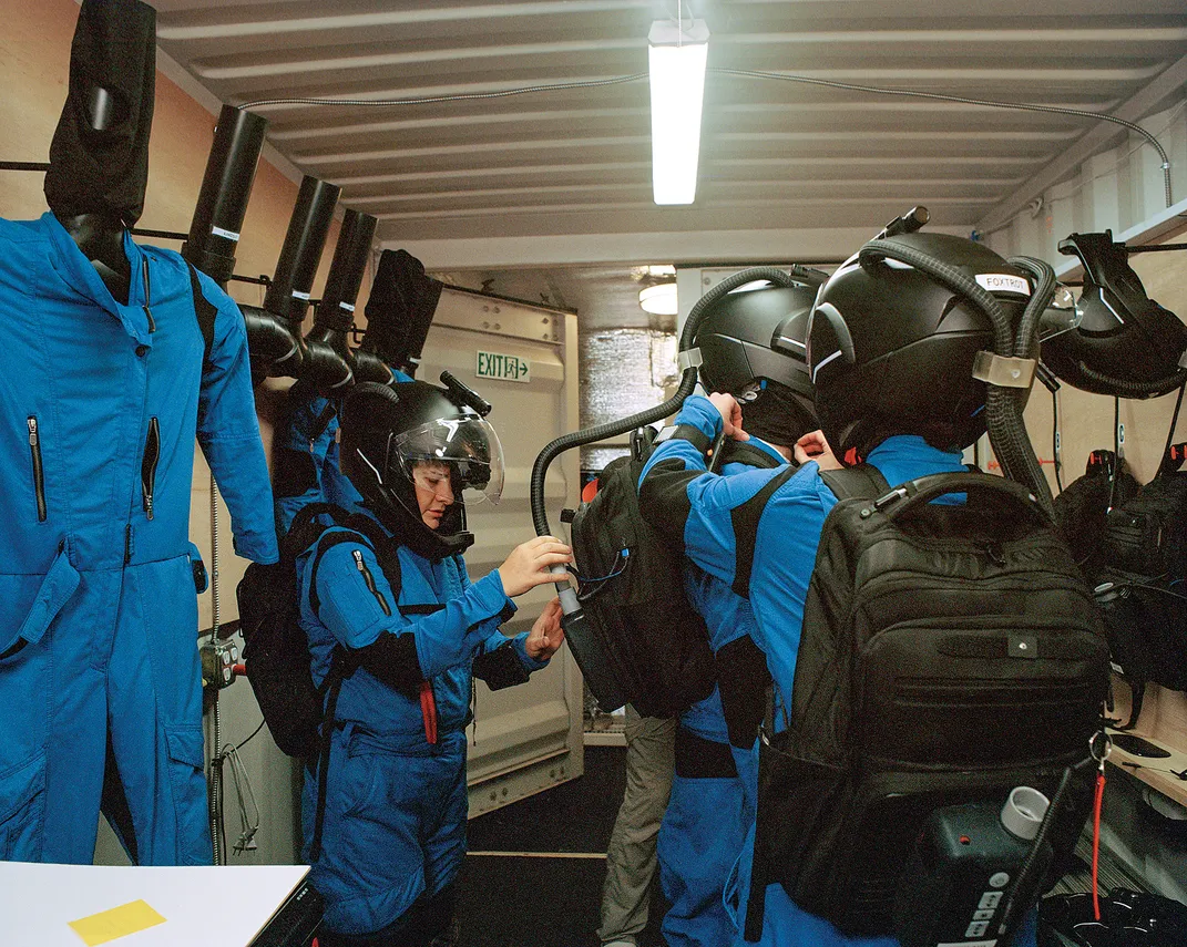 Crew members don spacesuits.