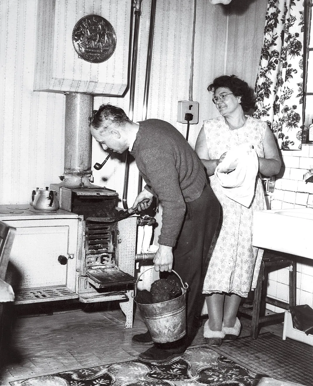 a man puts coal into a stove