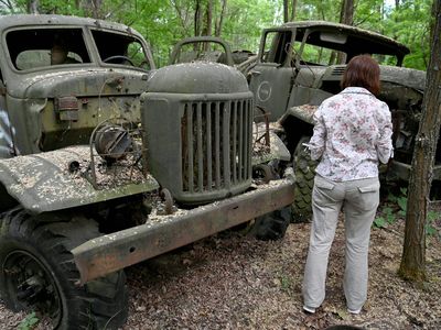 A woman looks at wreckage of trucks in the ghost city of Pripyat during a tour in the Chernobyl exclusion zone on June 7, 2019.