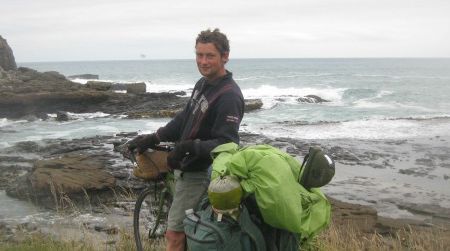 The author facing off with the edge of the world, where the gray and blustery waters of the Southern Ocean meet the rocks of Curio Bay, in the Catlins.