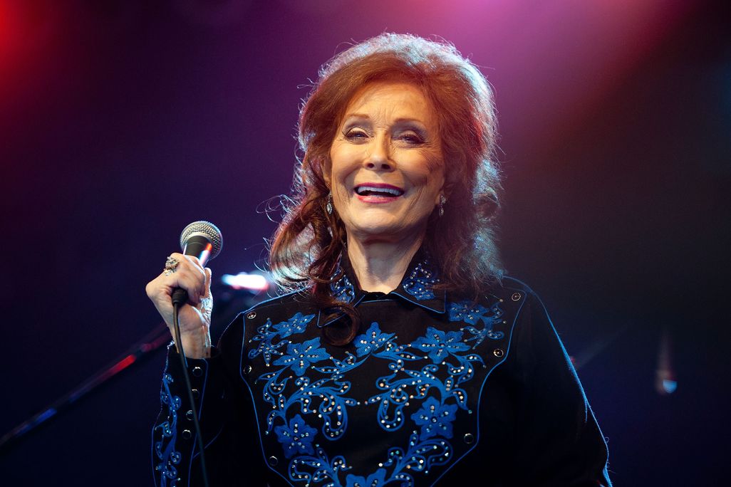 Loretta Lynn laughs while holding a microphone