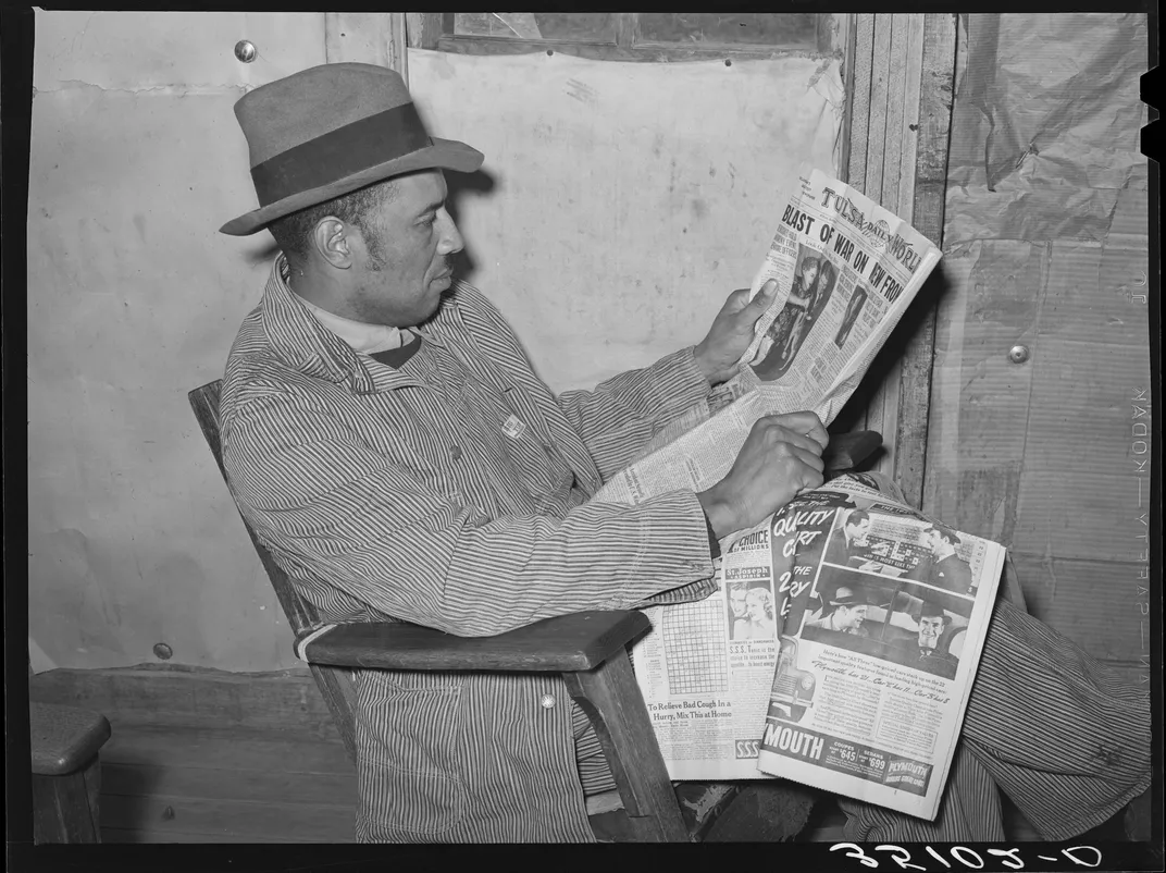 A tenant farmer in Oklahoma reads newspaper articles about the war in February 1940.