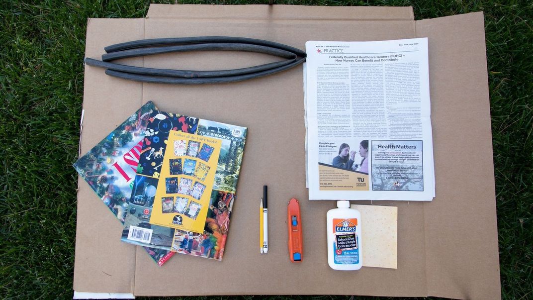 Cardboard on grass with books and papers on top.