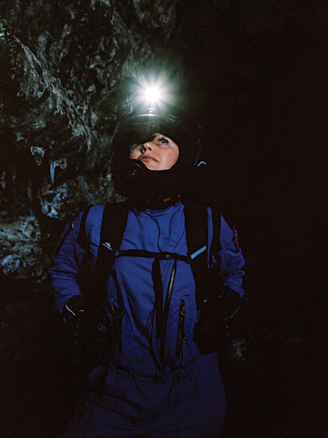 A woman looks up at the inside of a lava tube