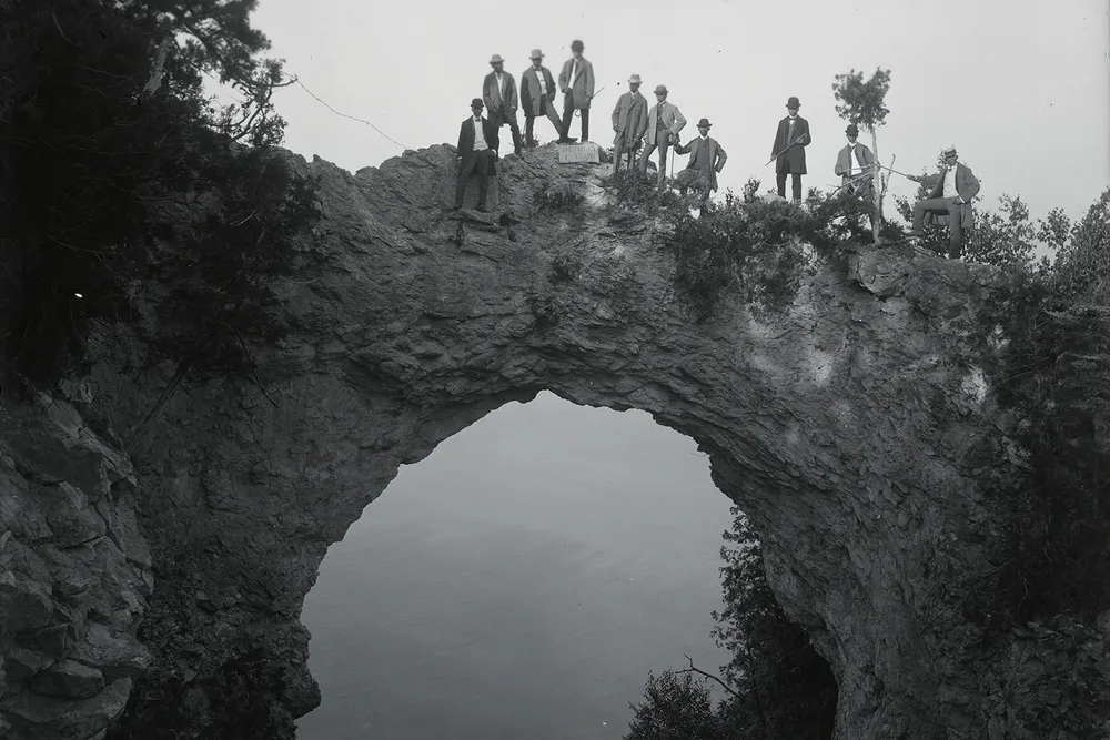 Visitors pose atop Arch Rock, a geological formation on Mackinac Island