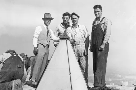 Man posing with construction workers at the top of the Washington Monument. The first restoration of the Monument began in 1934 as a Depression-era public works project. 