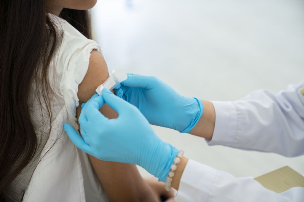 person putting bandaid on a child's arm after receiving a vaccine