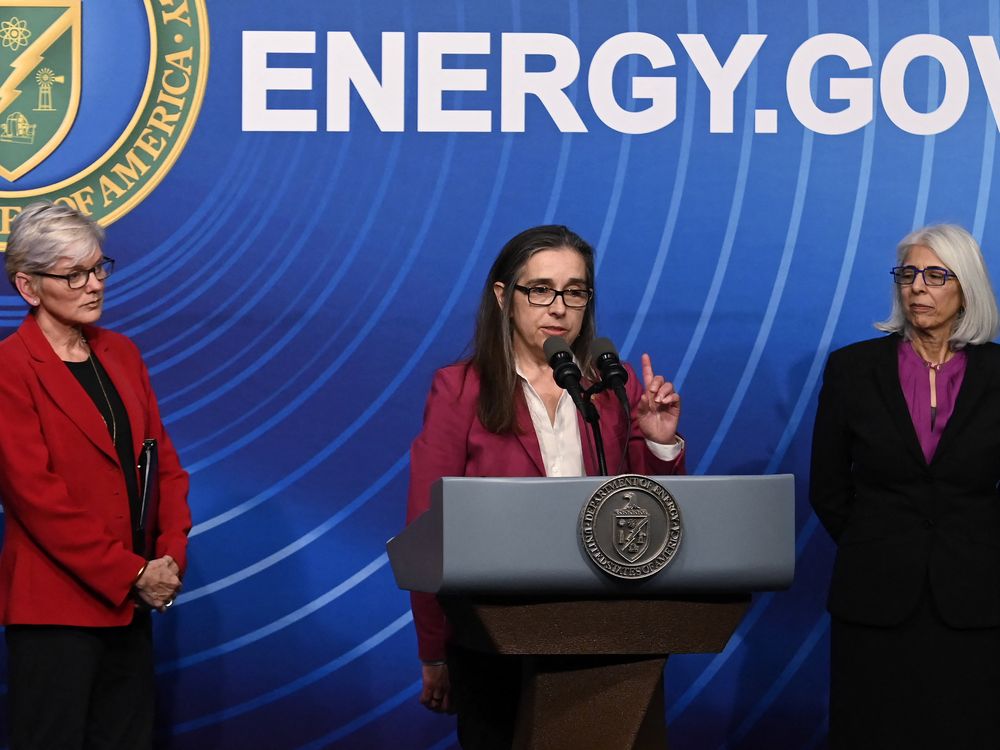 three women at a podium in front of a wall that reads energy.gov