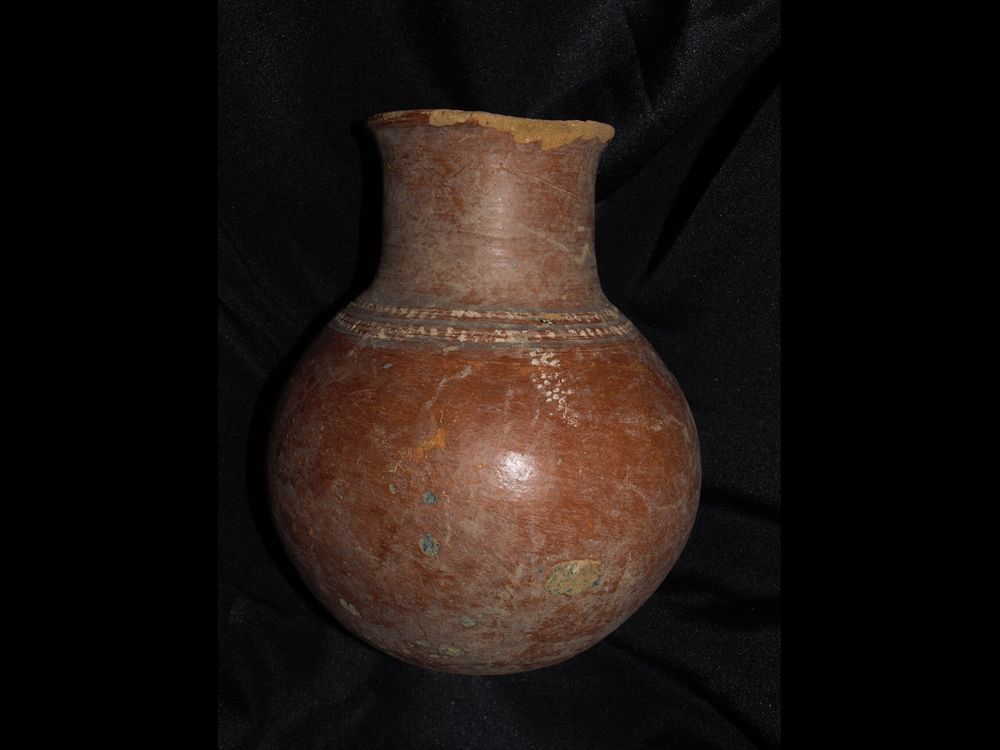 A reddish high-necked pot with some painting and visible cracks; mostly reddish-brown with specks of green and blue