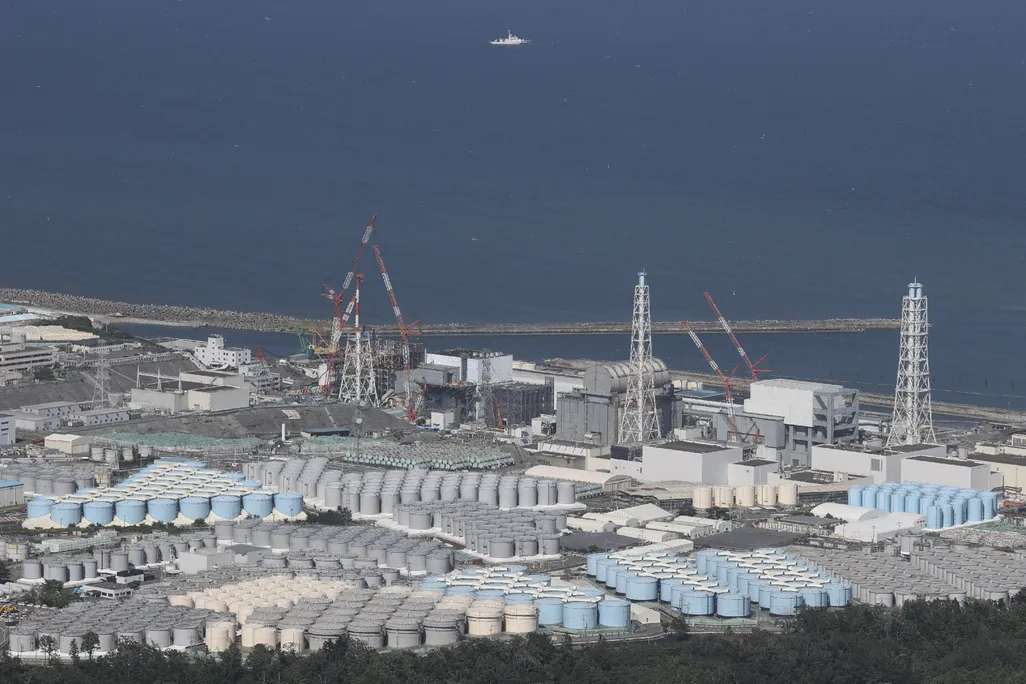 rows of blue, white and grey tanks next to the coast