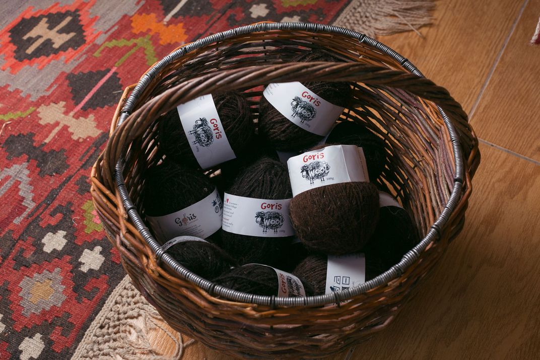 In a wooden basket are placed several skeins of brown wool from the Goris wool company.