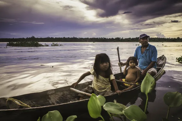 Dos niñas y su padre llegan en canoa a la orilla del caño turístico de la zona mientras cae el sol. Delta del Orinoco, Edo. Delta Amacuro, Venezuela. thumbnail