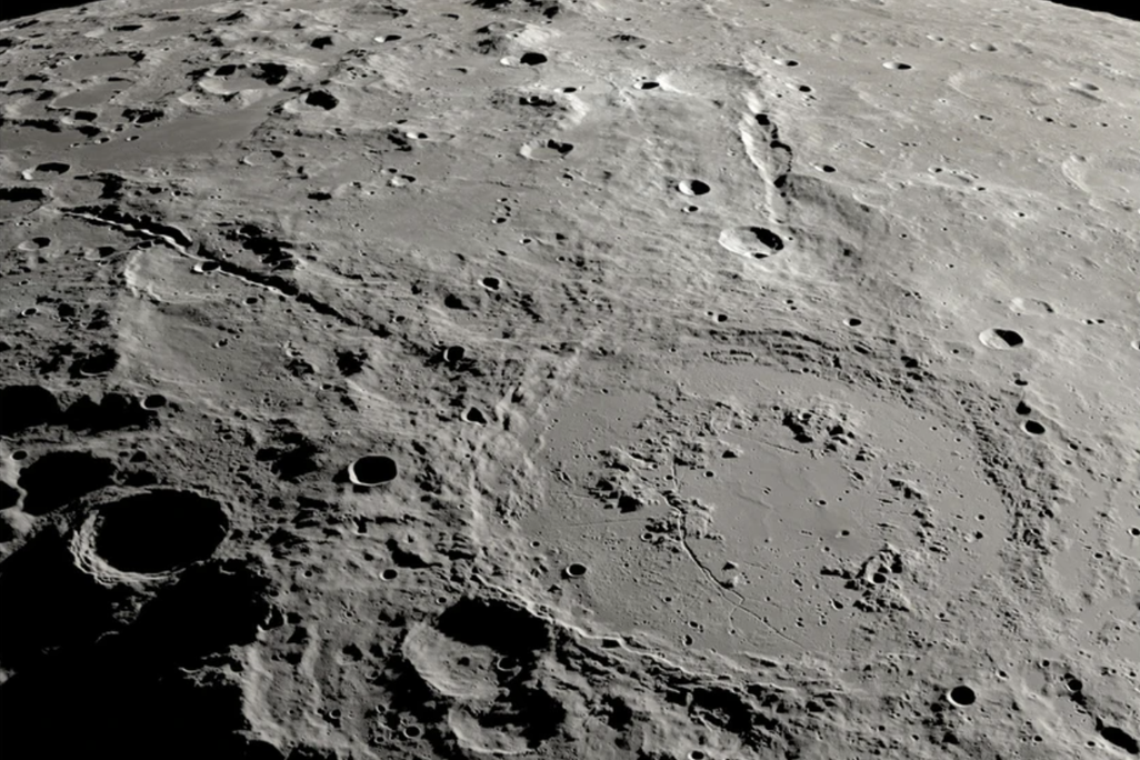 an overhead view of a large crater on the moon with two canyon lines stretching out from it