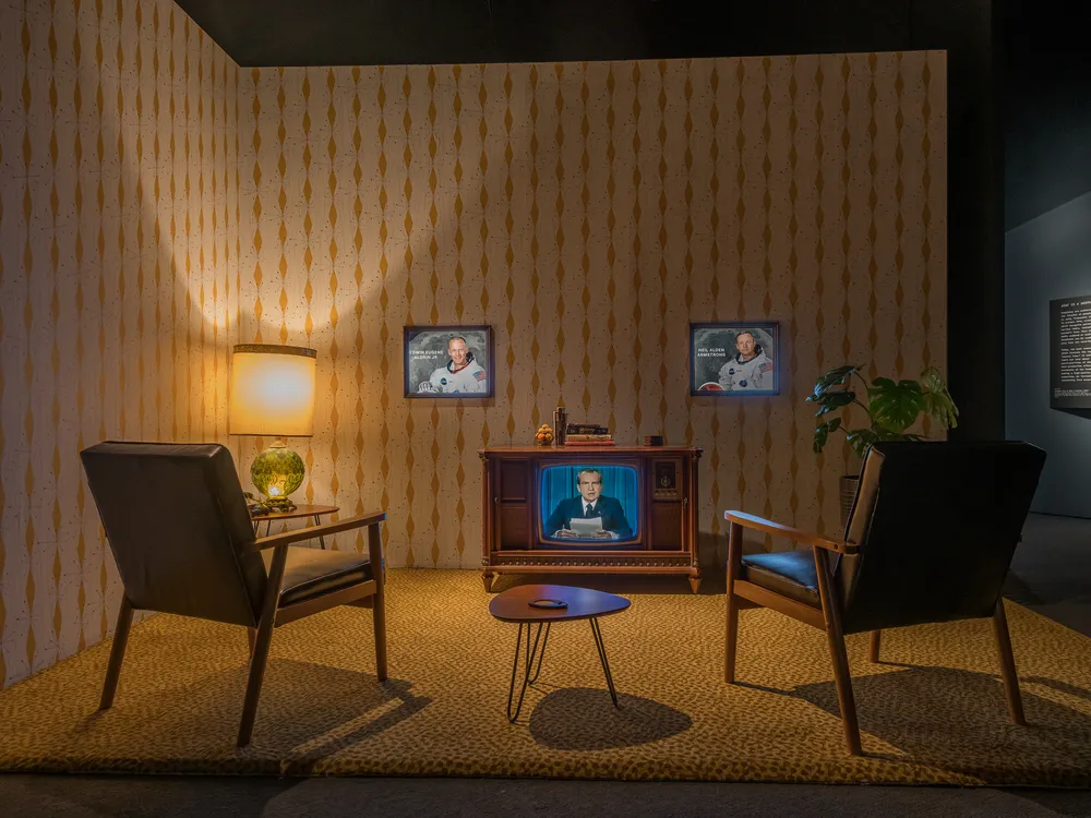 museum exhibit with two chairs and an old tv playing nixon footage