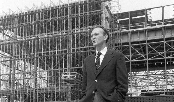 Michael Collins, the Museum's third director, stands before the steel skeleton of the new National Air and Space Museum in July 1974.