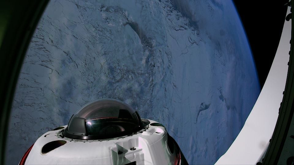 view looking down at polar ice from space out the window of a spacecraft, with a cupola on the craft visible in the foreground