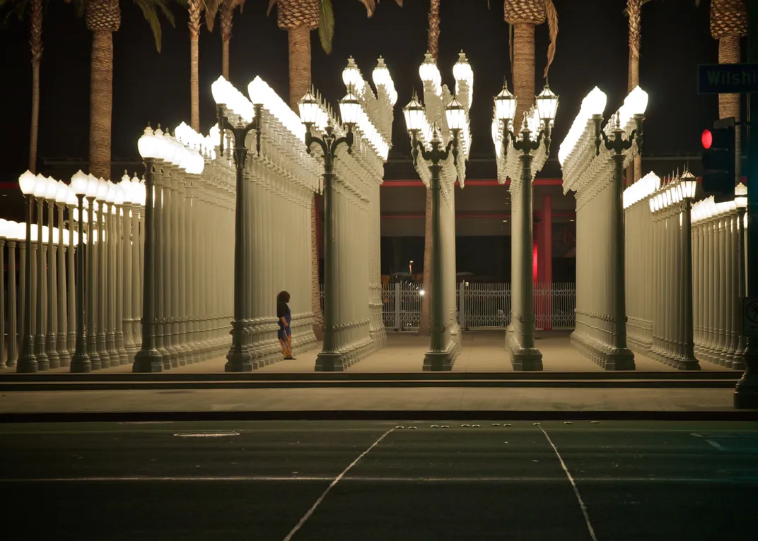 A series of light posts on a sidewalk at night