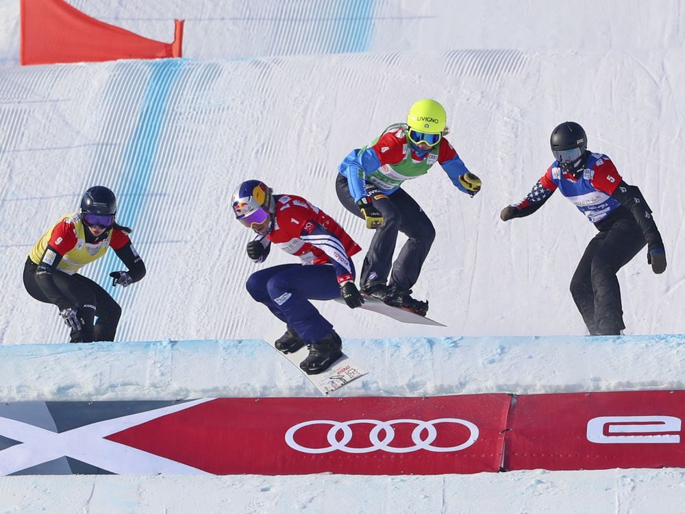 Four female snowboarders compete on a course.