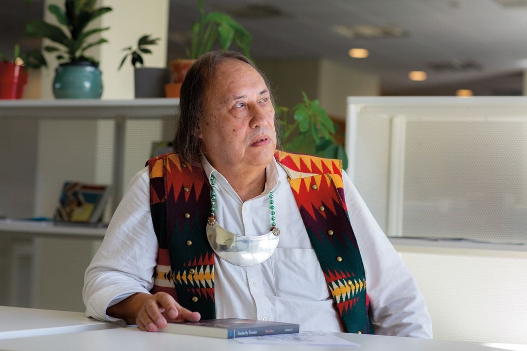 a man in a colorful vest sits for a portrait