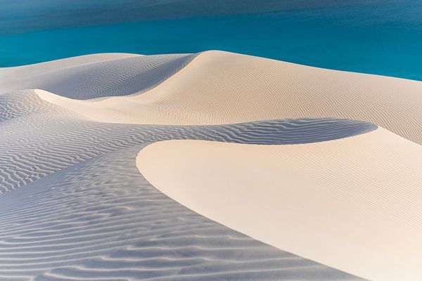 Snow-white Arher dunes gently descend into turquise waters of the Arabian sea. thumbnail