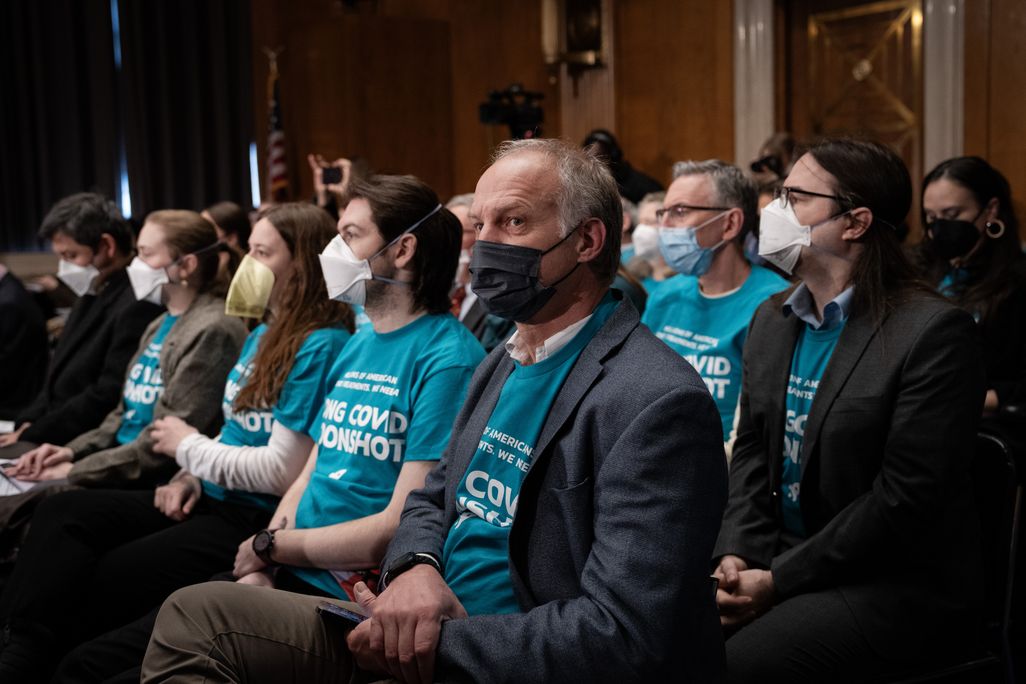 People with masks and blue t-shirts sitting in rows