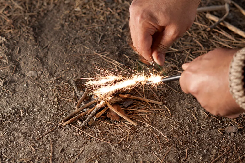 a pair of hands lighting kindle with flint