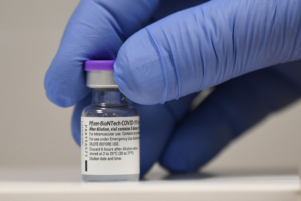 A vial of Pfizer's covid-19 vaccine being held by a gloved hand. 