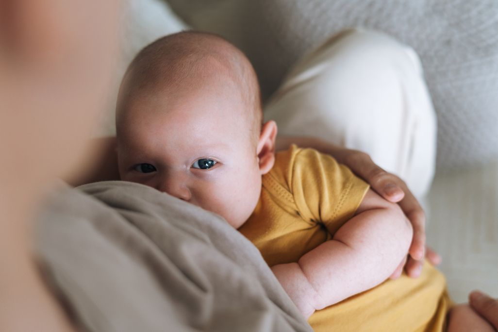 A mother breastfeeds a baby at home