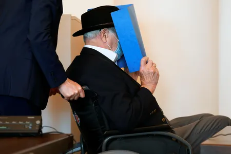 Bruno Dey, a former SS watchman at the Stutthof concentration camp, hides his face behind a folder as he arrives for a hearing in his trial on July 23.
