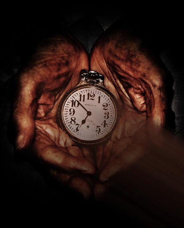 Aged hands holing an antique pocket watch thumbnail