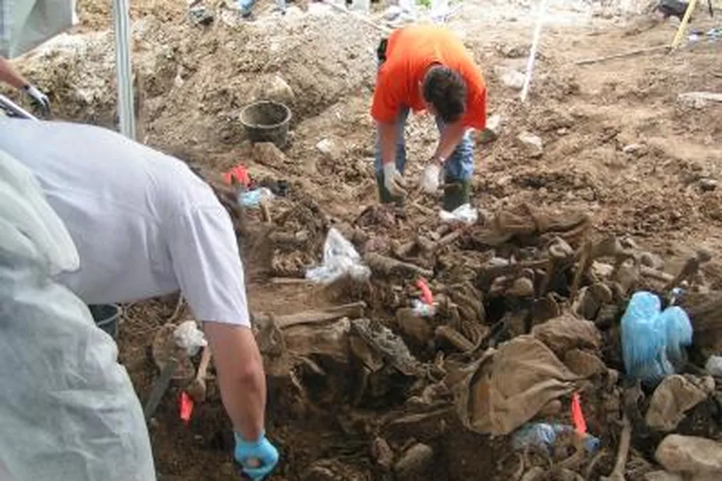 Workers examine remains at a mass grave in eastern Bosnia in 2004.