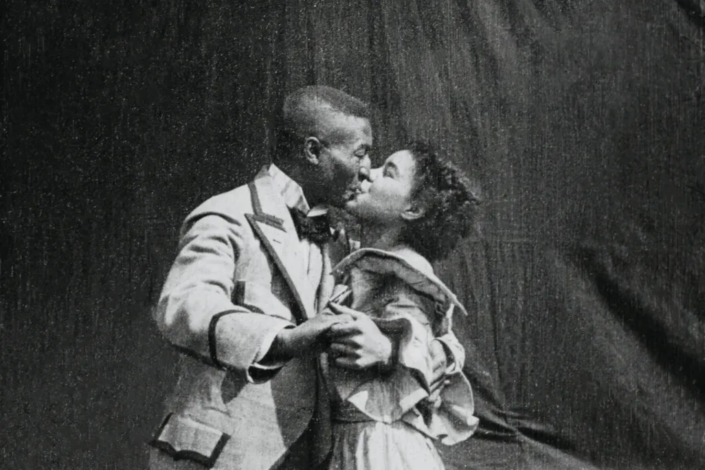 Black and white image of a black man and a black woman kissing