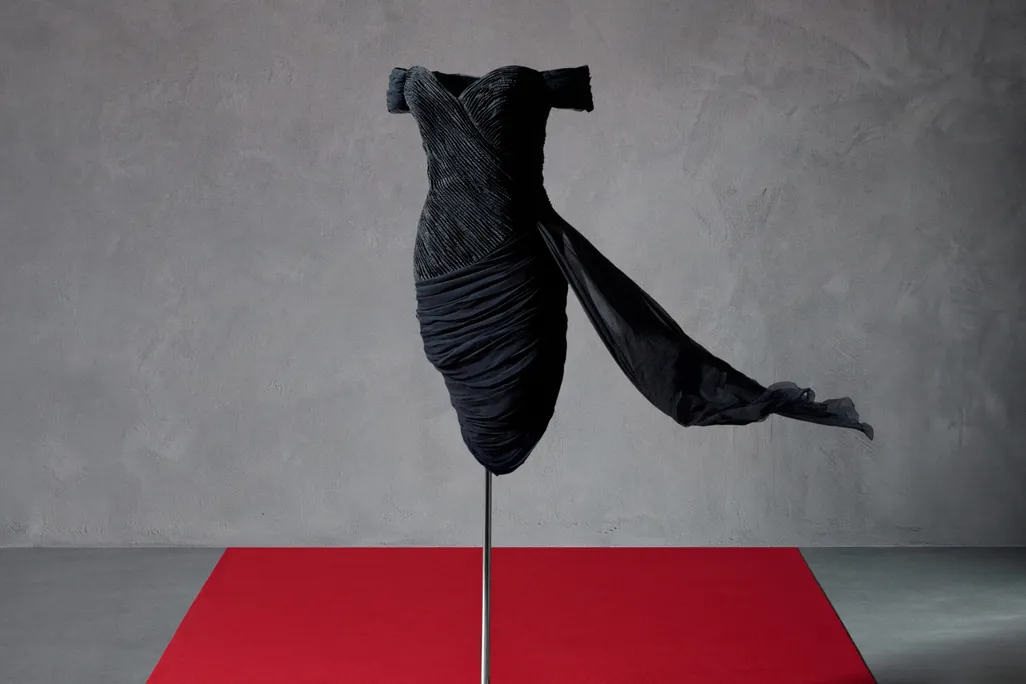 A black dress on a stand with some red carpeting below it