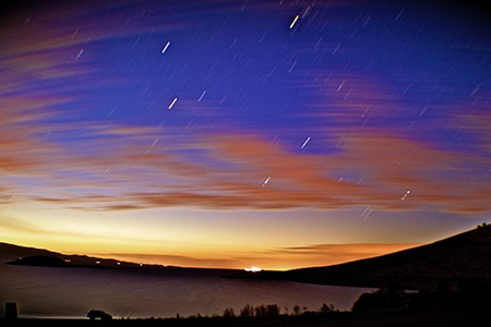 A dark sky just after dusk is set ablaze by several streaking meteorites