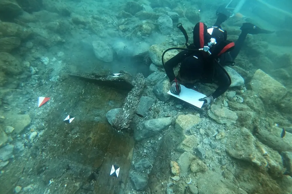 Underwater diver studying a wooden shipwreck