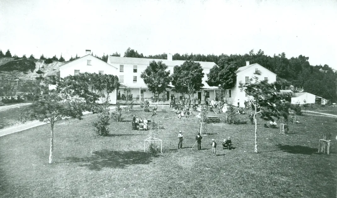People relaxing in the yard of the Mission House on Mackinac Island
